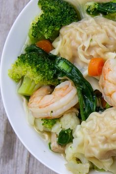 a white bowl filled with shrimp, broccoli and carrots