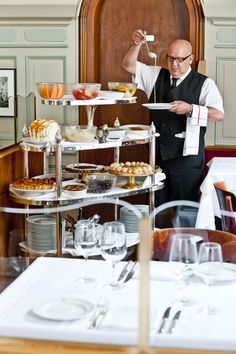 a man holding a plate with food on it in front of other plates and glasses