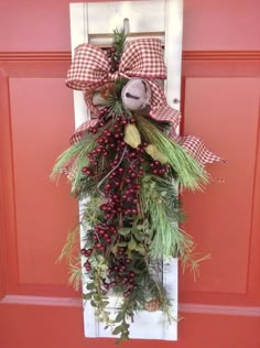 a door hanger decorated with berries, pine cones and a stuffed animal on it