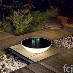 an outdoor table with two green cups on it in the middle of a wooden deck