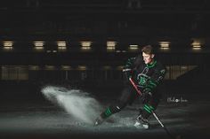 a young man playing ice hockey on an indoor rink in front of a building at night