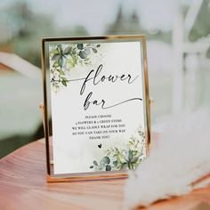 a flower bar sign sitting on top of a wooden table