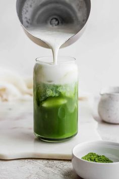 a person pouring green liquid into a jar