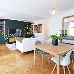 a living room filled with furniture and a wooden table in front of a mirror on top of a hard wood floor