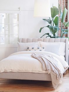 a bed with white linens and pillows in a room next to a brick wall