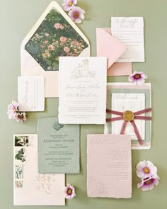 the wedding stationery is laid out on top of each other, including pink and green flowers