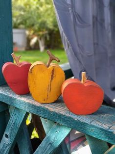 three wooden apples sitting on top of a blue bench