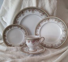 a white and gold china dinner set on a bed