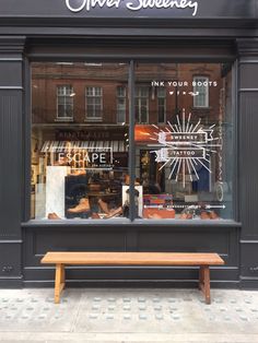 there is a wooden bench in front of the store window that sells shoes and other items