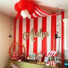 a red and white striped wall with balloons, candy bars, and decorations on it