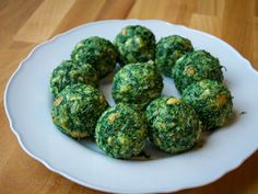 a white plate topped with broccoli balls on top of a wooden table