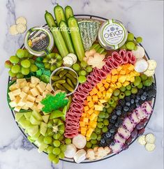 a platter filled with assorted fruits and veggies on top of a marble counter