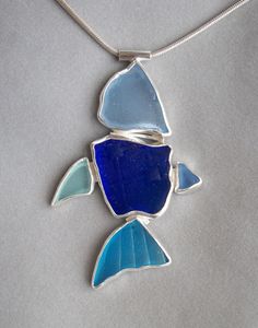 a blue and white fish pendant on a silver chain