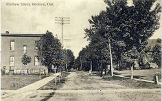 an old black and white photo of a street in the early 20th century, with trees on both sides