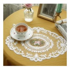 a tea cup and saucer on a table with a lace doily around it