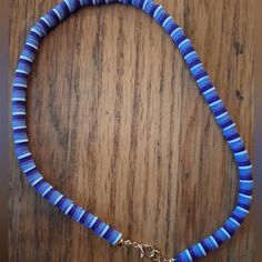 a blue and white beaded necklace on a wooden table