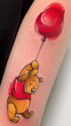 a winnie the pooh tattoo with a red balloon attached to it's arm