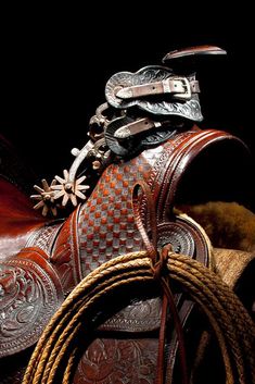 an old western saddle with rope and tacks on it's back, against a black background