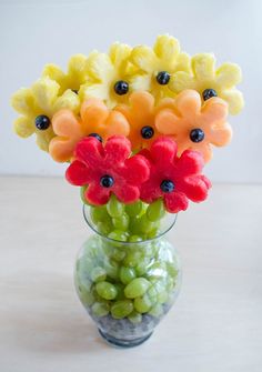 a glass vase filled with fruit and flowers