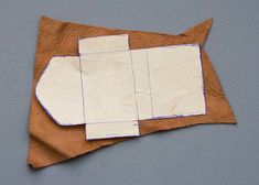 an origami fish made out of paper on a piece of brown fabric with white strips