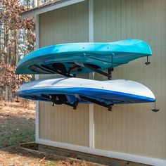 two blue and white kayaks hanging from the side of a building