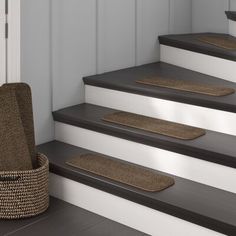 a set of stairs with carpet mats on them and a basket next to the steps