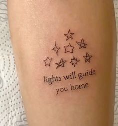 a woman's leg with stars and the words lights will guide you home on it