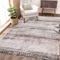 a living room area with a chair, rug and potted plant on the floor