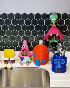 toys are sitting on the kitchen counter next to the sink and faucet holder