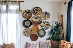 a living room filled with lots of different types of baskets hanging on the wall next to a window