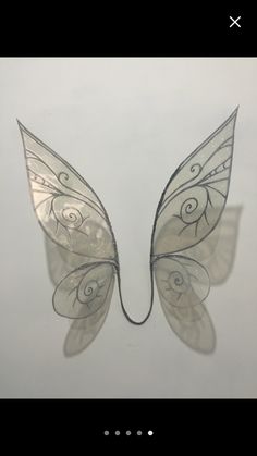 a metal butterfly sculpture sitting on top of a white table next to a phone screen