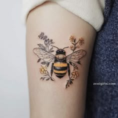 a woman's arm with a bee and flowers tattoo on the back of it