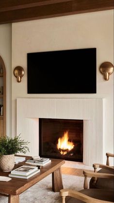 a living room with a fire place in the center and a flat screen tv above it