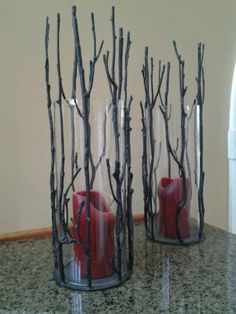 two vases with red candles in them sitting on a counter next to each other