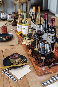 a wooden table topped with lots of bottles of wine and plates filled with desserts