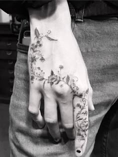 black and white photo of a person's hand with flowers tattooed on the palm