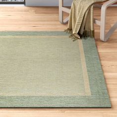 a green rug on the floor with a chair and table in the corner behind it