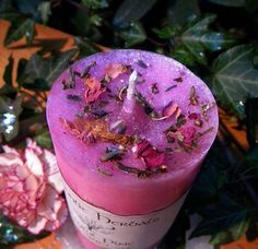 a candle with flowers on it sitting next to some leaves