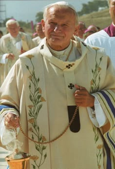 an older man wearing a priest's robe and holding a cup in his hand