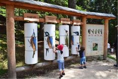 two young children are playing with refrigerators in front of a wooden structure at the park