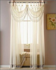 the curtains are hanging in front of the window with white drapes on it and a bench below