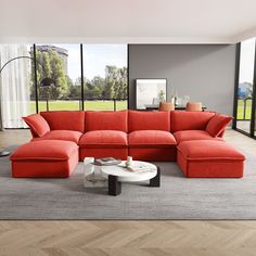 a living room with a large red couch and coffee table in front of the window