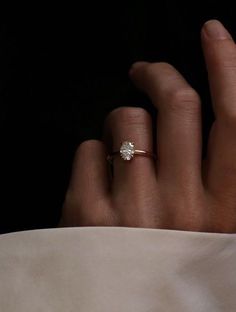 a woman's hand with a diamond ring on top of her finger, in black and white