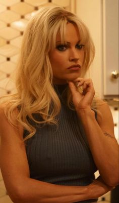 a woman with long blonde hair sitting at a table in front of a counter top