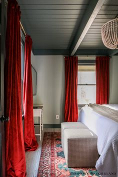 a bedroom with red drapes hanging from the ceiling