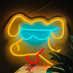 a neon sign that is sitting on top of a table next to a potted plant