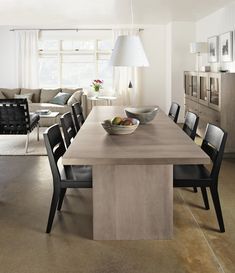 a dining room table with chairs and a bowl of fruit on it