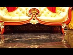 an ornately decorated couch sitting on top of a black marble floor next to a red curtain