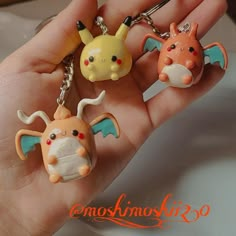 three different shaped key chains in someone's hand, one with a pikachu figure on it