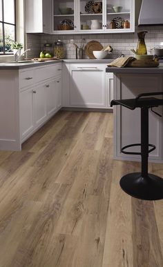 a kitchen with white cabinets and wood flooring on the counter top, along with a bar stool